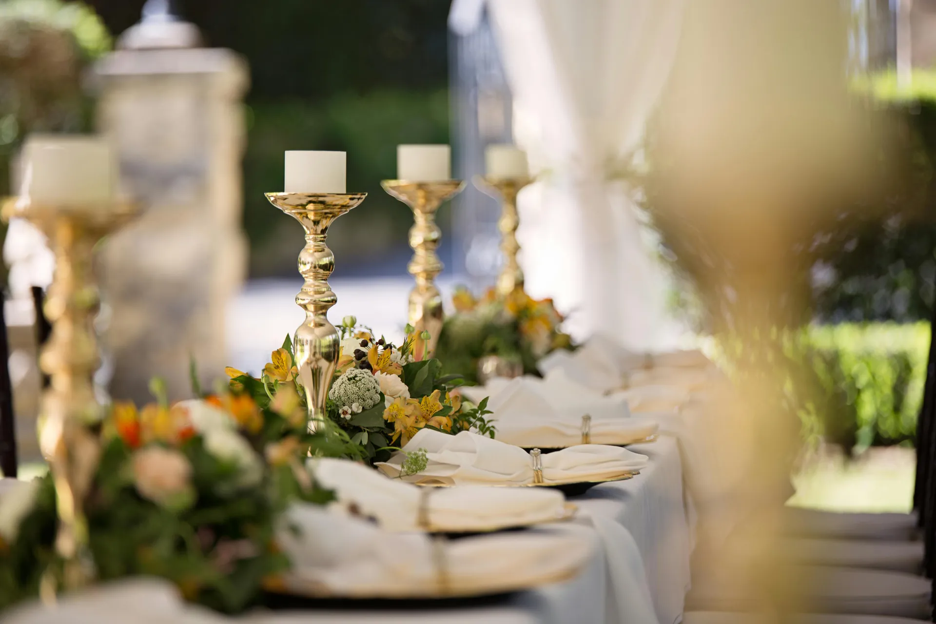 Luxurious outdoor wedding table setting with elegant floral arrangements and candlesticks